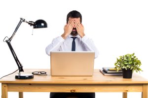 Businessman in his office covering his eyes Businessman in his office covering his eyes